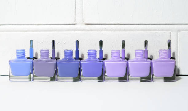 Set of open blue tint nail polish bottles with brushes. Group of nail polish on white wall background. Copy space. stock photo