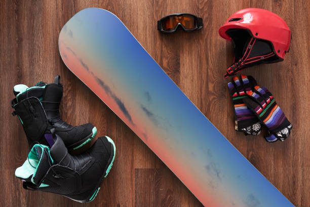 set of snowboard boots, helmet, gloves and mask on wooden stock photo