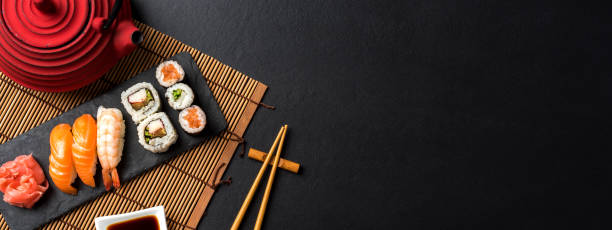 eingestellt von sushi mit wasabi, sojasauce und teekanne auf schwarzem stein - kannestein stock-fotos und bilder