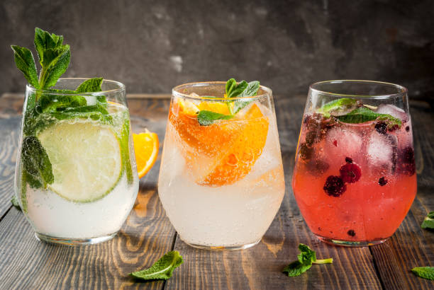 Set of three kinds of gin tonic Selection of three kinds of gin tonic: with blackberries, with orange, with lime and mint leaves. In glasses on a rustic wooden background. Copy space vodka soda stock pictures, royalty-free photos & images