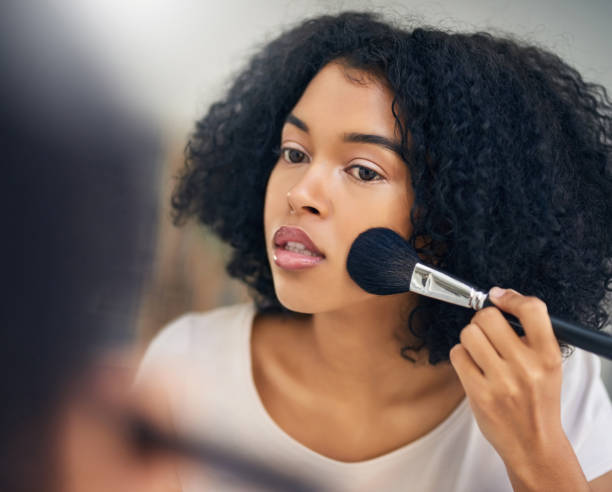 Setting the foundation for flawless makeup Shot of a beautiful young woman applying makeup with a brush at home applying blush stock pictures, royalty-free photos & images