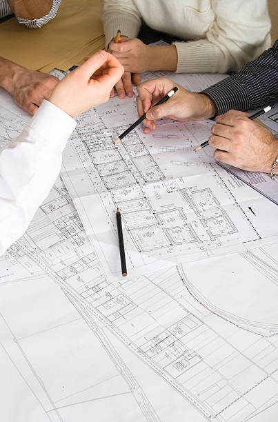 Several pairs of hands working together on blueprints stock photo
