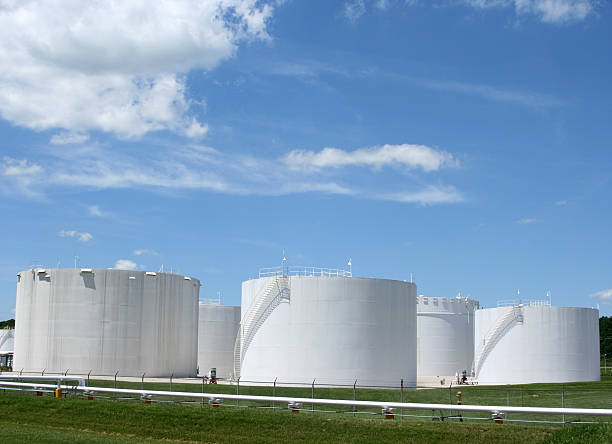 Several white storage tanks in a grassy field White storage tanks under a blue sky. Gasoline, oil, or other storage. oil refinery factory stock pictures, royalty-free photos & images