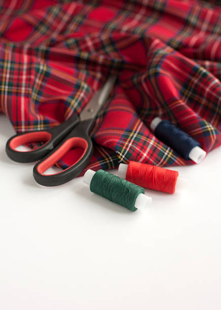 Sewing accessories: tartan fabric, scissors and sewing threads stock photo