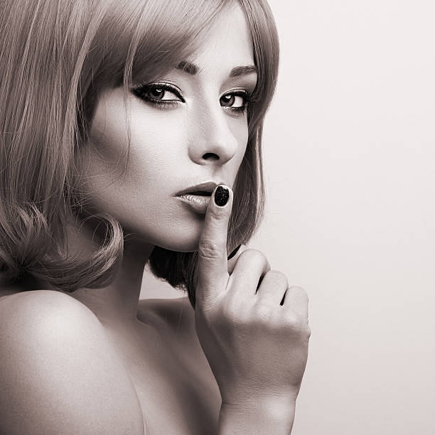 Sexy beautiful makeup blonde famale model showing secret sign stock photo