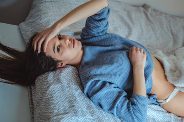 Sexy girl in sweater lying on the bed stock photo