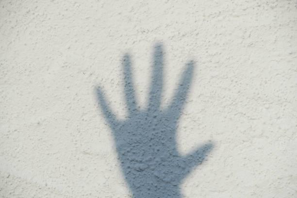 Shadow of a hand on a white wall. Five fingers. Stop. stock photo