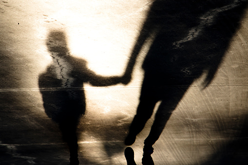 Shadow silhouettes of father and son walking hand in hand