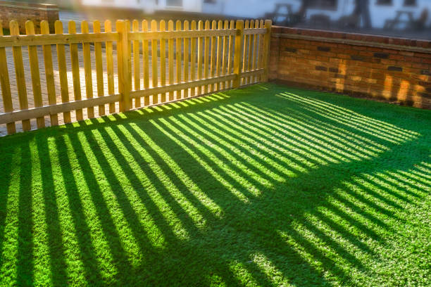 shadows of a wooden picket fence on an artifical grass lawn stock photo