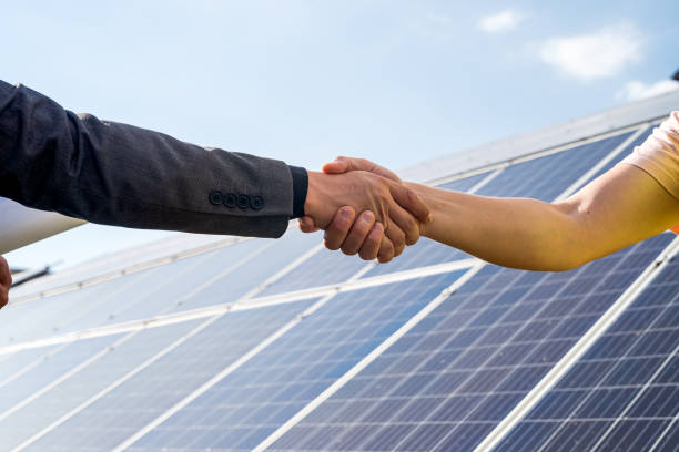 shaking hands against solar panel  after the conclusion of the agreement in the renewable energy stock photo