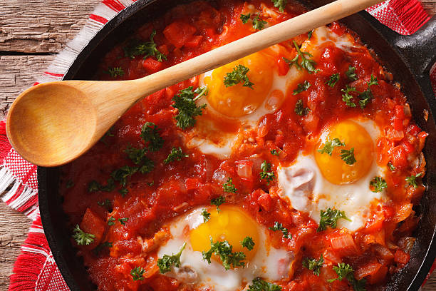 Shakshuka fried eggs macro in frying pan. horizontal top view Shakshuka fried eggs macro in a frying pan. horizontal view from above poached food photos stock pictures, royalty-free photos & images