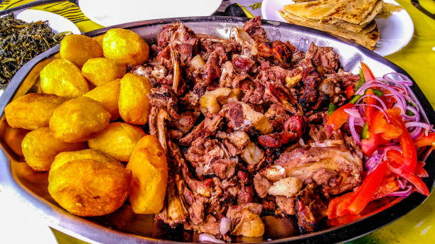 Sharing platter of a traditional Kenyan dish, Nyama choma and accompaniments of kachumbari salad, sukuma wiki, chapati and roast potatoes. stock photo