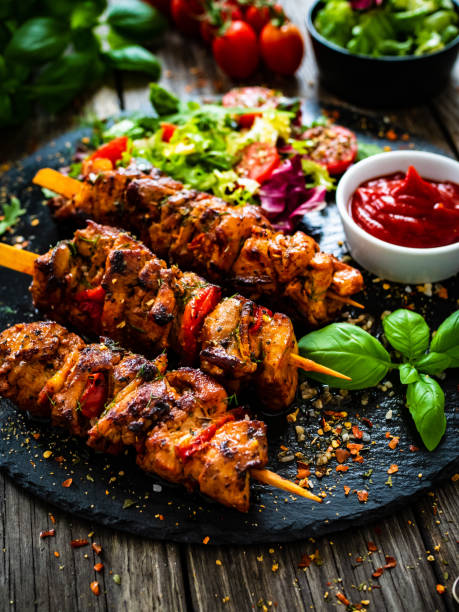 Shashlik - grilled meat and vegetables on stone plate on wooden table stock photo