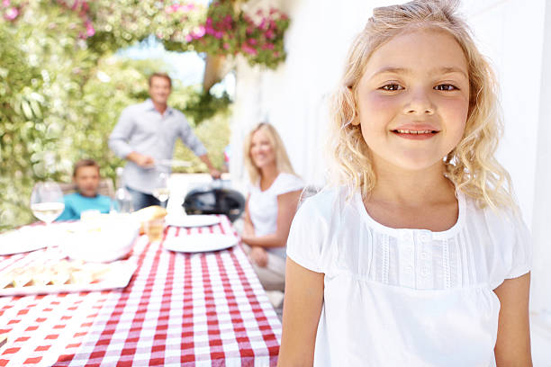 A cute young girl having lunch with her family outdoors