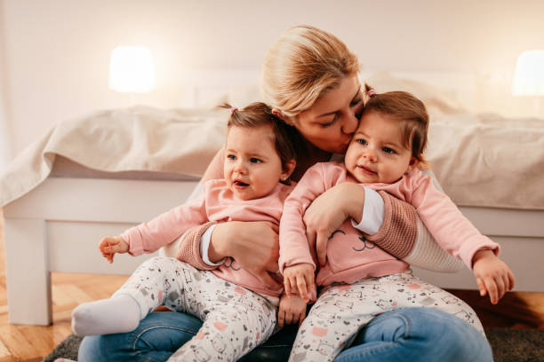 She loves them so much Mother holding two baby girls twins stock pictures, royalty-free photos & images