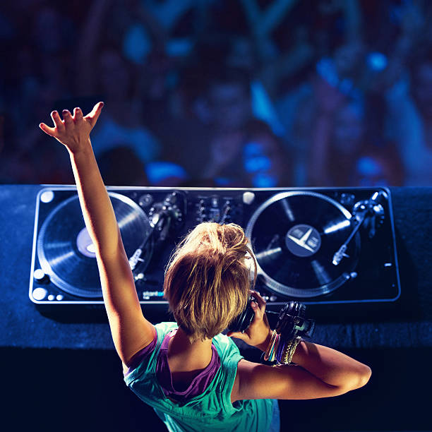 She makes the crowd go wild! Rear-view shot of a trendy young DJ mixing up some music with a crowd in the background club dj stock pictures, royalty-free photos & images