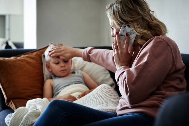 She's calling her doctor for expert medical advice Shot of a mother wearing a surgical mask making a phone call while aiding to her sick young son at home illness stock pictures, royalty-free photos & images