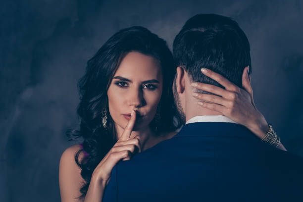 Shh! Portrait of tempting brunette lady showing silence sign with forefinger touching secret mysterious gentlemen with rear view, lovely Mr and Mrs isolated on grey background  betrayal stock pictures, royalty-free photos & images