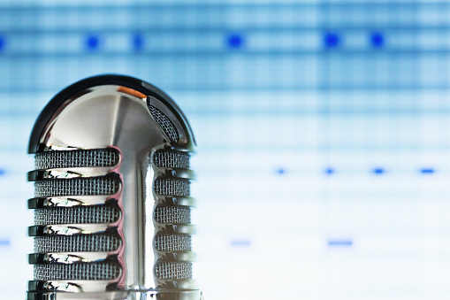Old-fashioned-looking microphone with recording software blurred in the background.