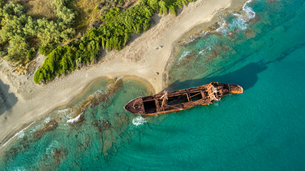 Shipwreck on coast of south Peloponnese Huge rusty shipwreck stranded on rocks on the long sand beach of south Peloponnese in Greece. Wreck is in very bed condition, exposed to wind and waves.photo taken with drone peloponnese stock pictures, royalty-free photos & images