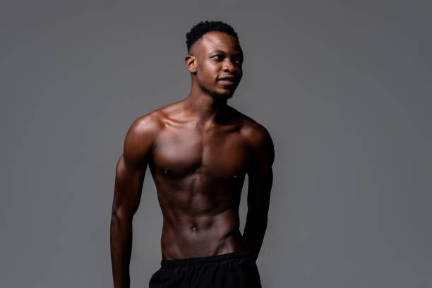 Shirtless young lean fit African man in isolated light gray background stock photo