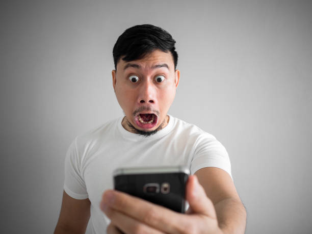 Shocked and scary face of man get yelled from smartphone.  See something scary in smartphone. stock photo