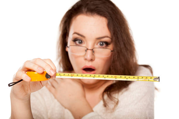 shocked by the size young woman is shocked by the size shown on the measuring tape human mouth gag adhesive tape women stock pictures, royalty-free photos & images