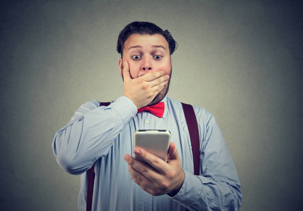 Shocked man having bad news on the phone Young man looking at his smartphone with deep feeling shocked and frightened. fat man looks at the phone stock pictures, royalty-free photos & images