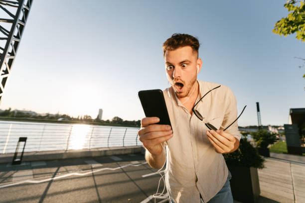 Shocked man reading message outdoors stock photo