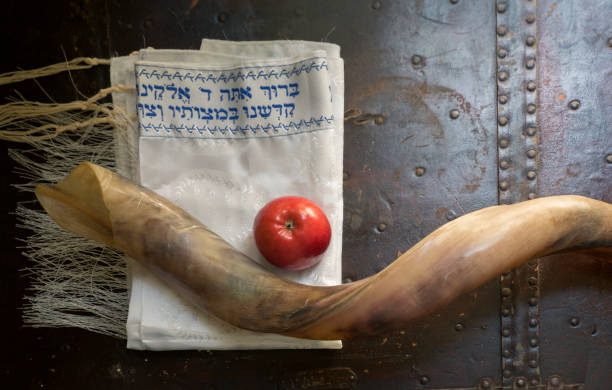 Close up of shofar ,Hebrew prayer book  and apple on a table- symbols for