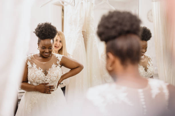 winkel assistent helpen bruid krijgen in trouwjurk - bruid stockfoto's en -beelden