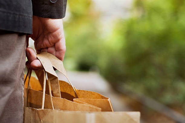 shopping background consumer basket, close up of paper shopping bags in male hand market retail space stock pictures, royalty-free photos & images