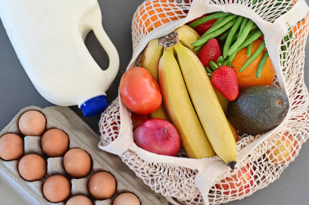 Shopping bag full of fresh vegetables and fruits with milk and eggs stock photo