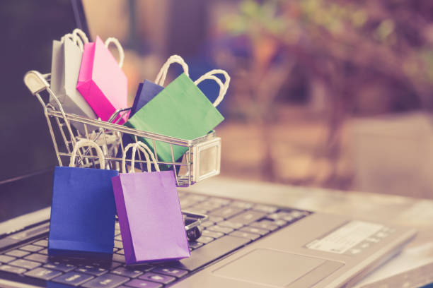 Shopping bags and a shopping cart on a laptop keyboard Online shopping / e-commerce and customer experience concept spending money stock pictures, royalty-free photos & images