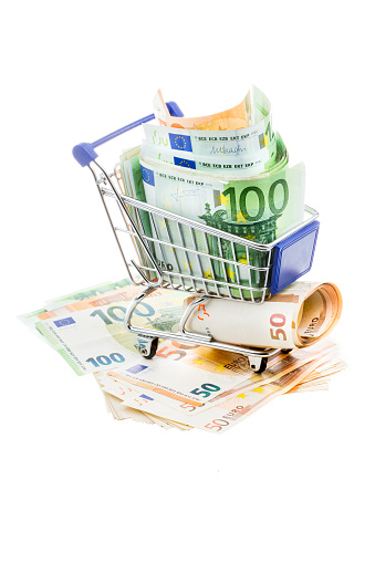 Shopping cart and Euro banknotes on white background