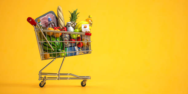 Shopping cart full of food on yellow background. Grocery and food store concept. stock photo