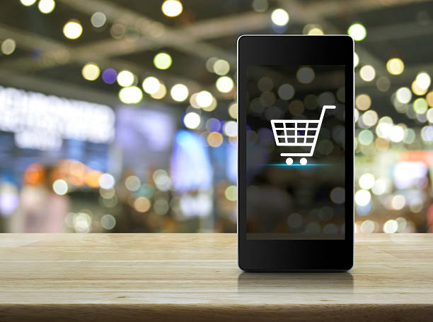 Shopping cart Icon on smart phone screen over blur mall stock photo