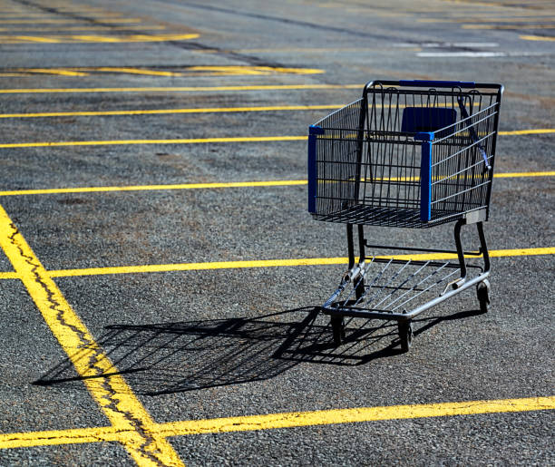 Shopping Cart Discarded shopping cart in a large parking lot. shopping cart parking lot stock pictures, royalty-free photos & images