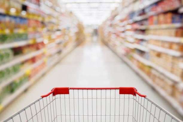 Shopping cart view in Supermarket aisle with product shelves abstract blur defocused background Shopping cart view in Supermarket aisle with product shelves abstract blur defocused background aisle stock pictures, royalty-free photos & images