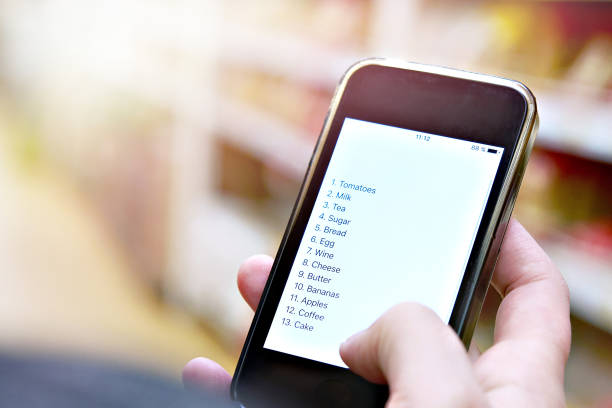 Shopping list on smartphone in hand of customer Shopping list on smartphone screen in the hand of women customers shopping list stock pictures, royalty-free photos & images