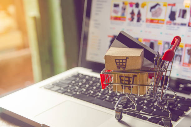 shopping online concept - parcel or paper cartons with a shopping cart logo in a trolley on a laptop keyboard. shopping service on the online web. with payment by credit card and offers home delivery. - compras em casa imagens e fotografias de stock