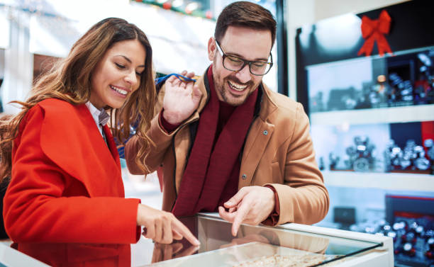 Shopping time. Young couple looking at jewels in jewelry shop. Consumerism, love, dating, lifestyle concept Shopping time. Young couple looking at jewels in jewelry shop. Consumerism, love, dating, lifestyle concept gold ring on finger stock pictures, royalty-free photos & images