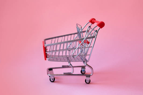 Shopping trolley on soft pink pastel background with copy space. stock photo