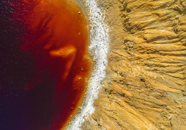 Shore of toxic red lake in abandoned open pit copper mine stock photo