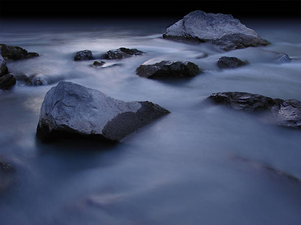 shore with rocks at night in silver moonlight stock photo