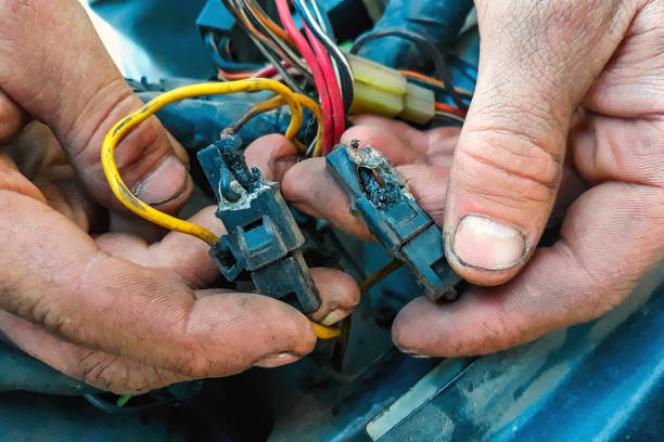 Short circuit in car. Male electrician holding a charred wires. Vehicle repair, car service station stock photo