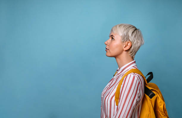Short haired woman looking up Short haired young woman looking up against a blue background. white hair young woman stock pictures, royalty-free photos & images