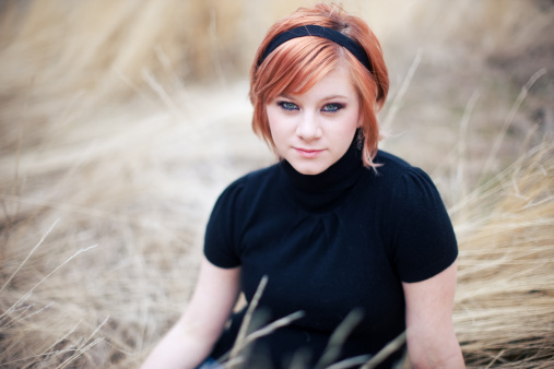 Short Haired Woman Sitting In Sunlit Tall Grass Stock Photo