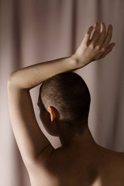Short-haired nude young woman with a raised hand. stock photo