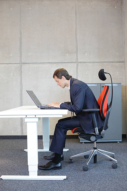 short-sighted business man bad sitting posture at laptop stock photo